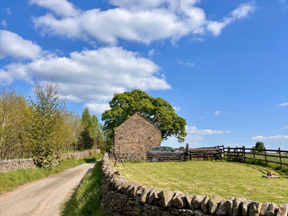 A stone building with a car parked near a fence at School House Cottage in Newtown near Longnor
