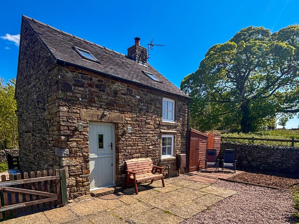 A stone house with a bench and chairs at School House Cottage Newtown near Longnor