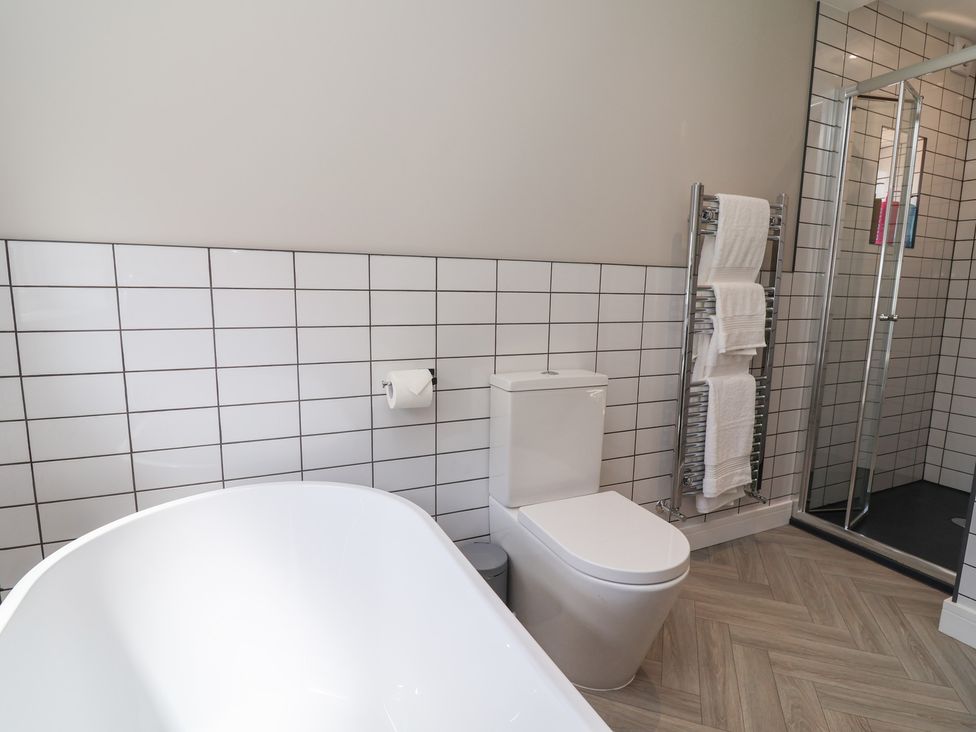 A bathroom with a bathtub, toilet, towel rack, and shower at 7 Grantham Road Southport