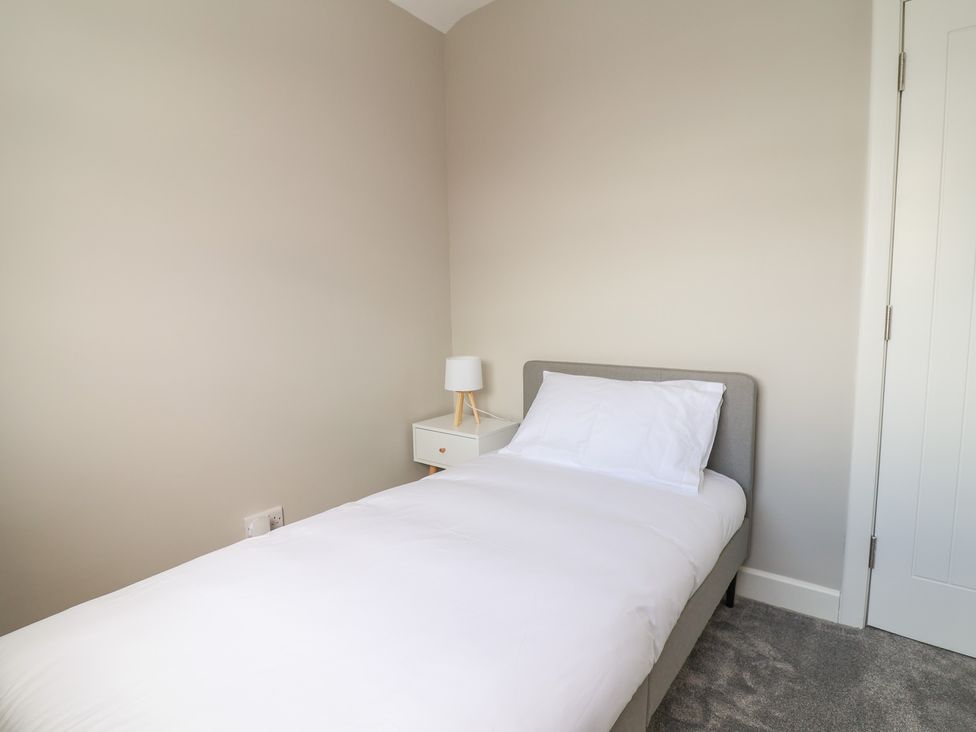 A bedroom with a single bed and a nightstand with a lamp at 7 Grantham Road Southport