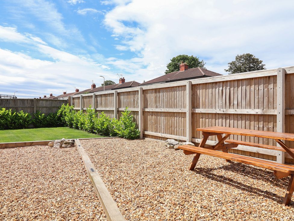 A garden with a wooden table and gravel at 7 Grantham Road in Southport