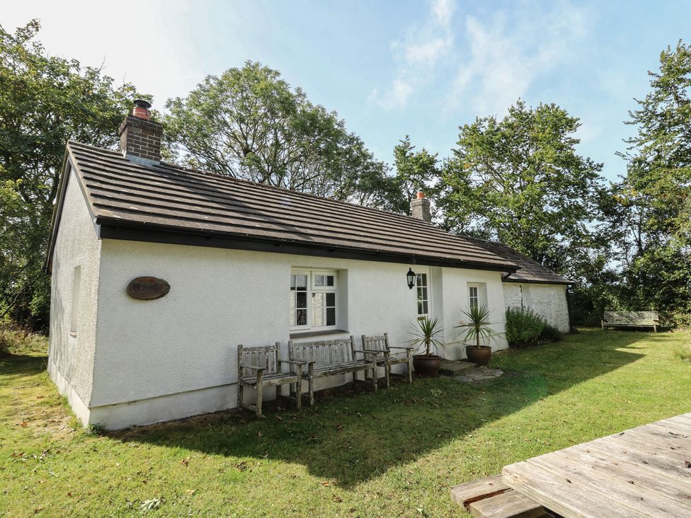 A house with a bench and potted plants in an outdoor space at Llainorfa in Maenygroes near New Quay