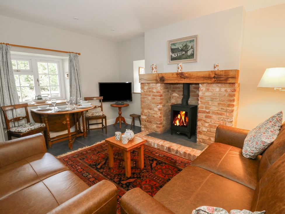 A living room with a fireplace and dining area at Llainorfa Maenygroes near New Quay