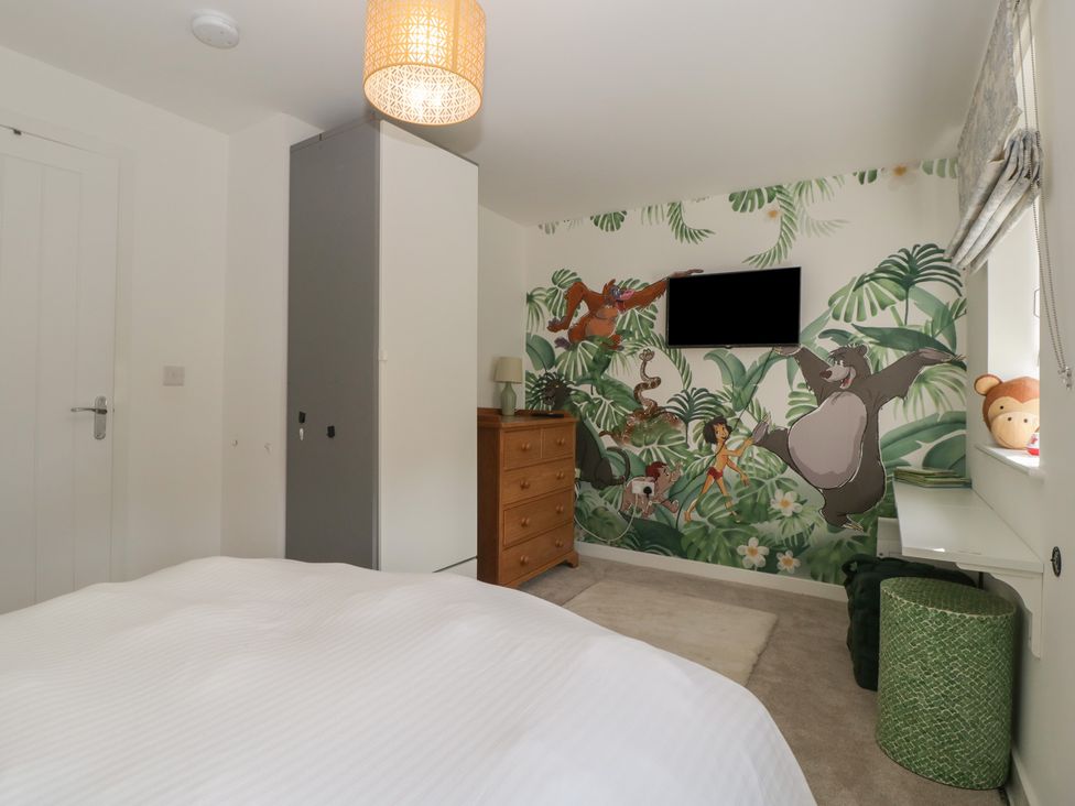 A bedroom with a wardrobe, dresser, and mural at 15 Hey Close in Malvern