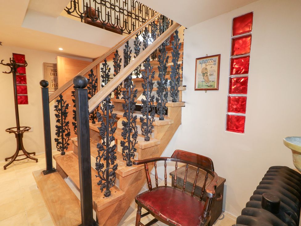 A staircase with a decorative handrail and a chair in the hallway at Crea The Mission Hall near Ballymena