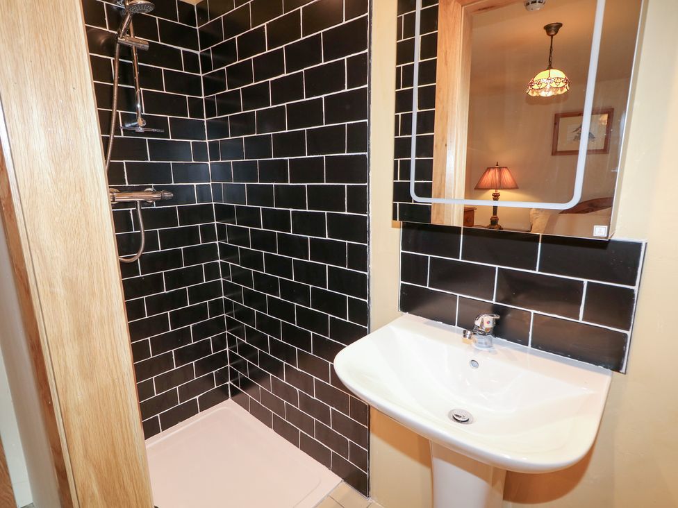 A bathroom with a shower, sink, and mirror at Crea The Mission Hall near Ballymena