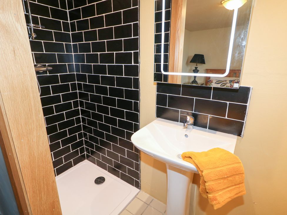 A bathroom with a shower, sink, and yellow towel at Crea The Mission Hall near Ballymena