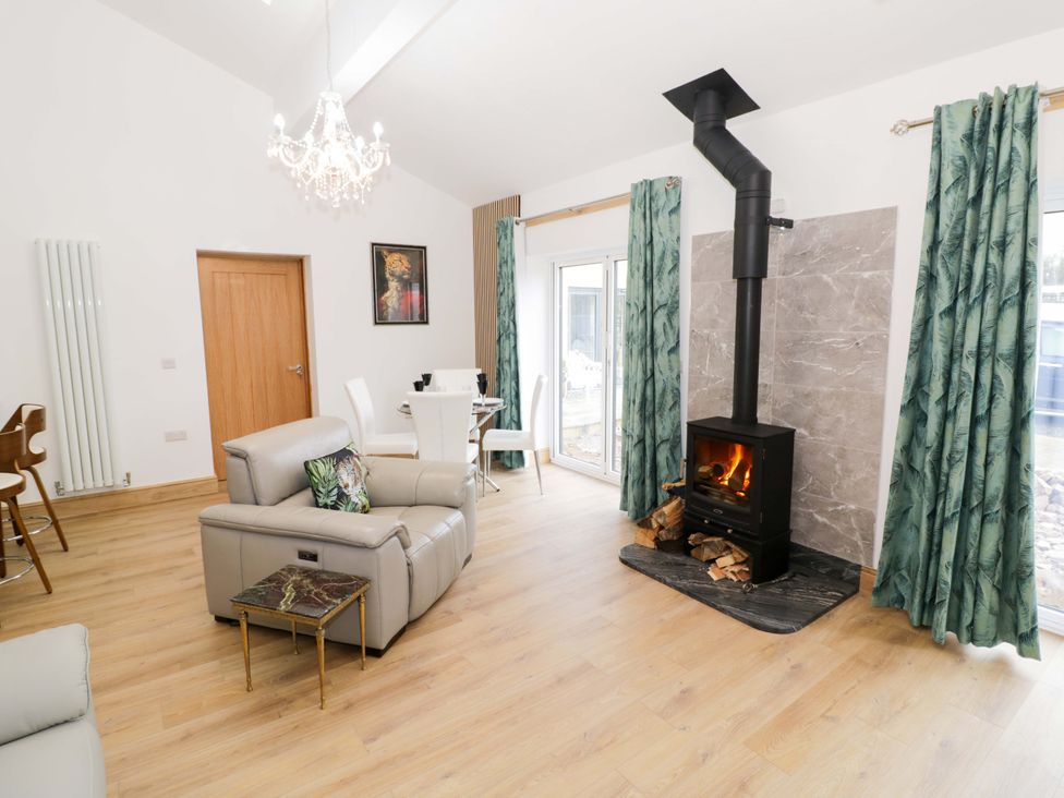A living room with a fireplace and dining area at The Barn in Astwood Bank