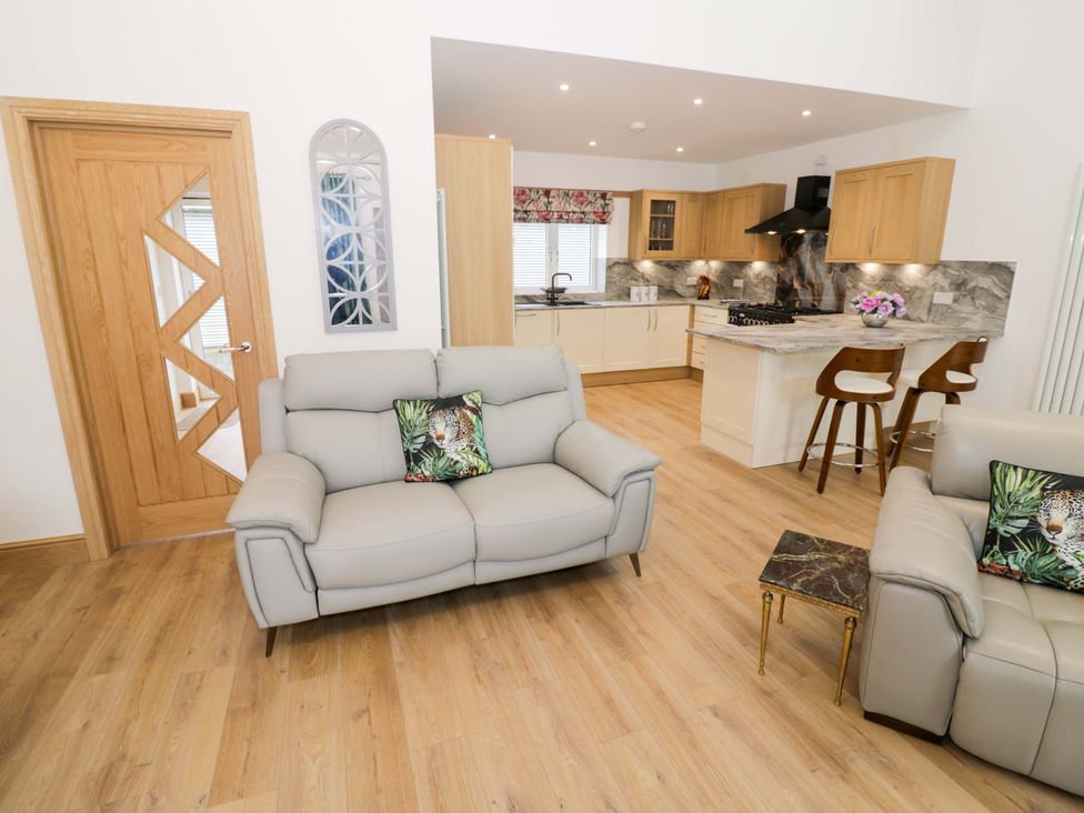 A living room with a sofa and kitchen area at The Barn in Astwood Bank