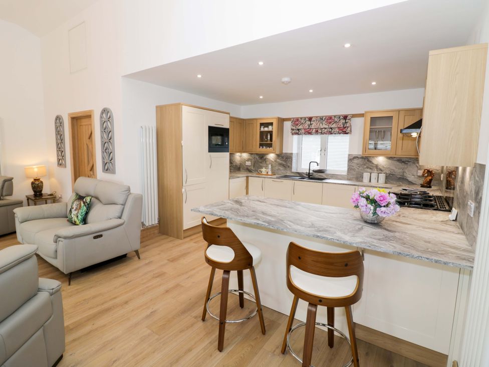 A kitchen with bar stools and a microwave at The Barn in Astwood Bank