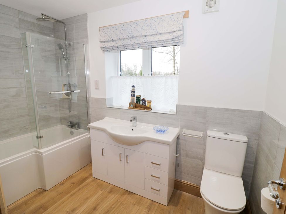 A bathroom with bathtub, shower, sink, and toilet at The Barn in Astwood Bank