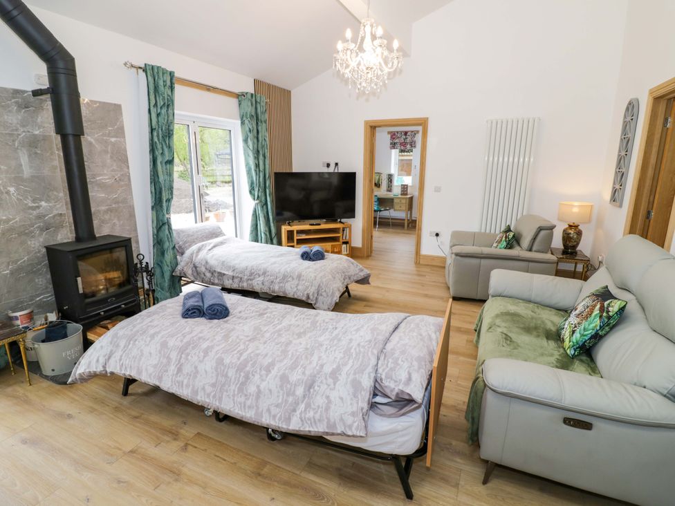 A living room with beds, sofa, and television at The Barn in Astwood Bank