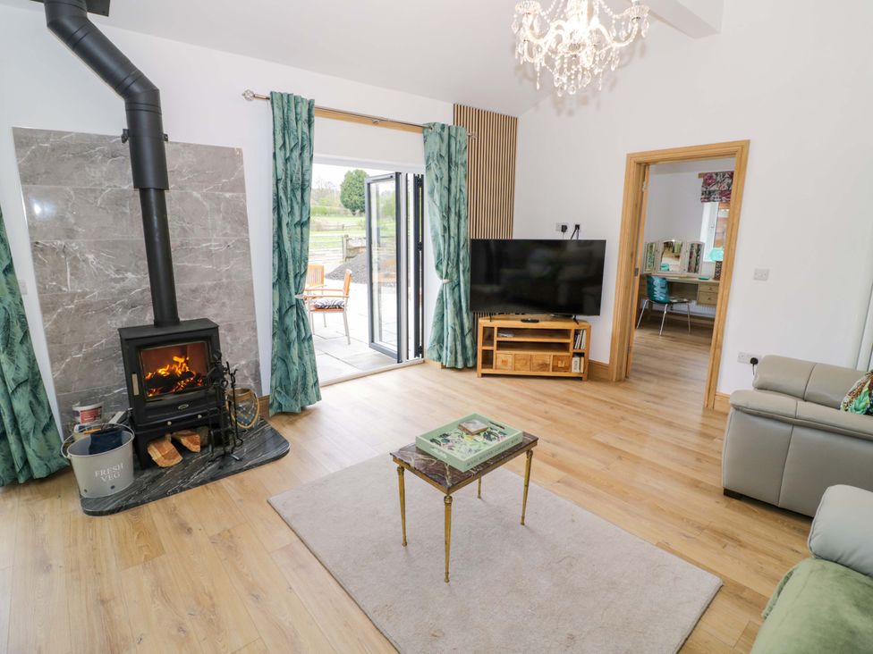 A living room with a stove and television at The Barn in Astwood Bank