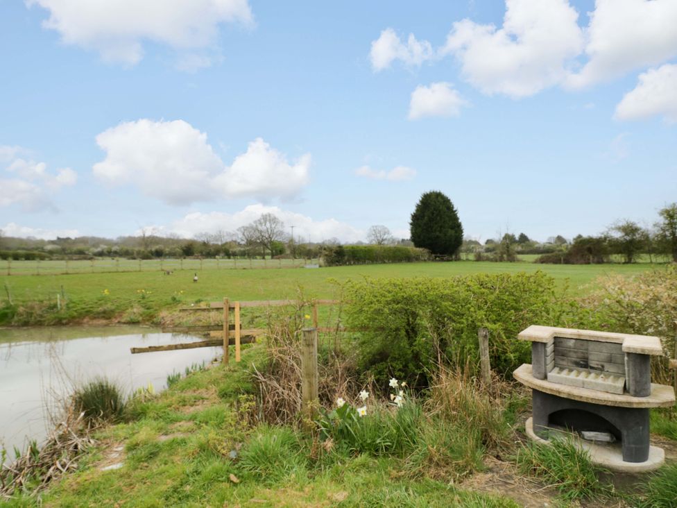 An outdoor area with a pond and a bench at The Barn in Astwood Bank