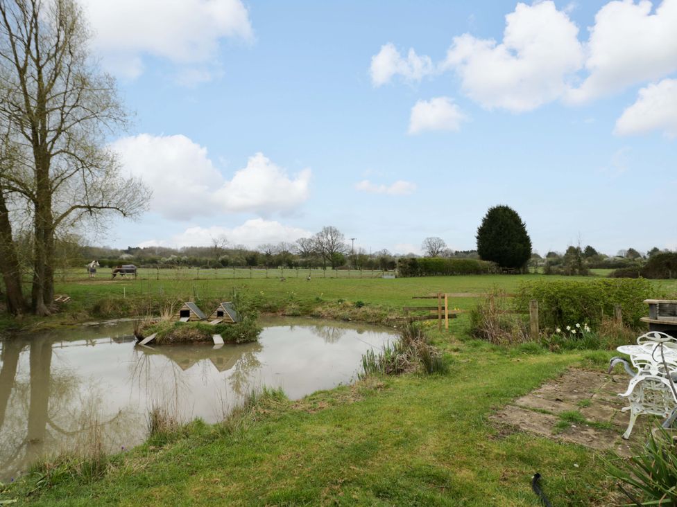 An outdoor area with a pond and chairs at The Barn in Astwood Bank