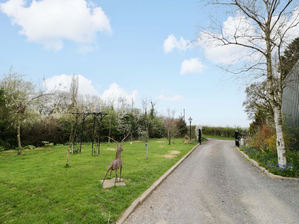 A garden with a deer sculpture and a pathway at The Barn in Astwood Bank