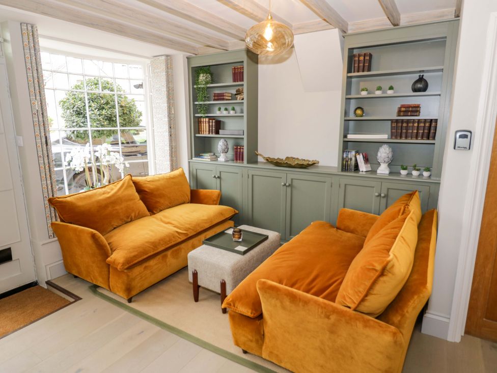 A snug with orange sofas and a coffee table at Bay House Cottage in Broadway