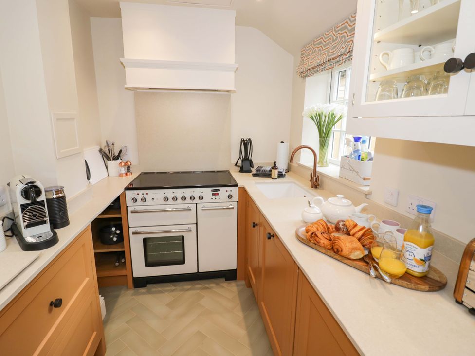 A kitchen with a stove, sink, cabinets, and breakfast items at Bay House Cottage in Broadway