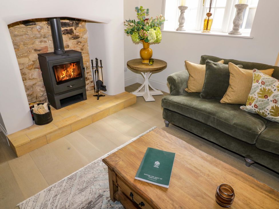 A living room with a log burner and a couch at Bay House Cottage in Broadway