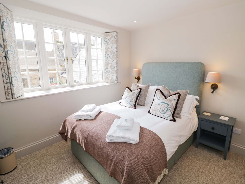 A bedroom with a bed and windows at Bay House Cottage in Broadway