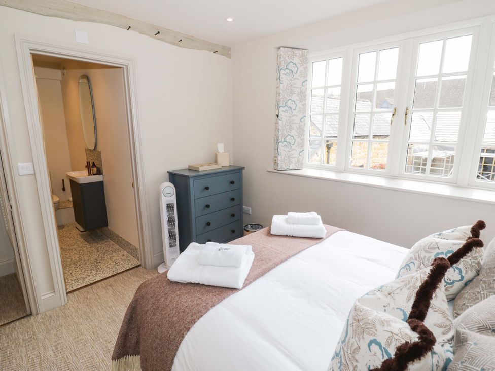 A bedroom with a bed and a bathroom door at Bay House Cottage in Broadway