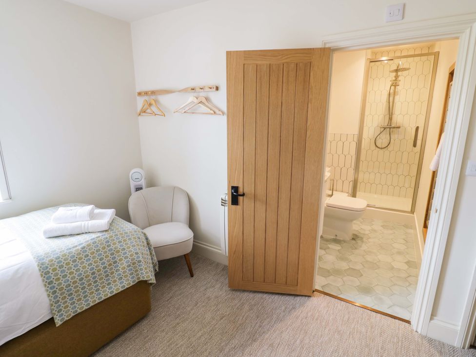 A bedroom with a bed and an adjoining bathroom at Bay House Cottage in Broadway