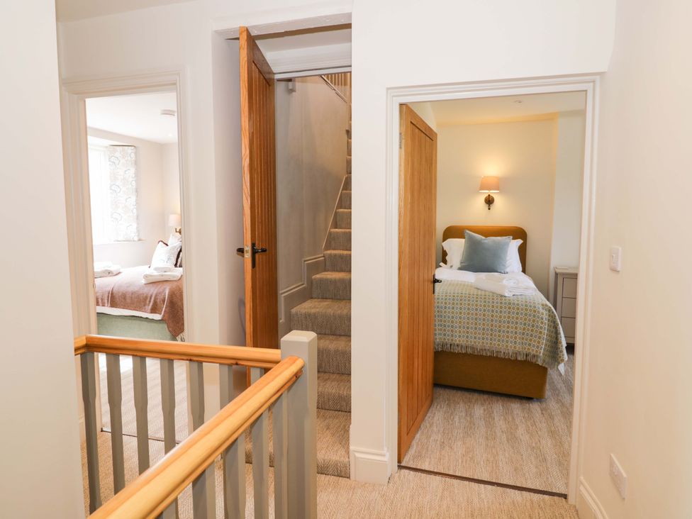 A hallway with doors to bedrooms and stairs at Bay House Cottage in Broadway