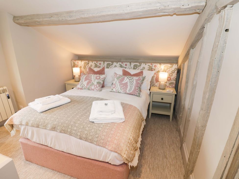 A bedroom with a bed, nightstand, and lamp at Bay House Cottage in Broadway