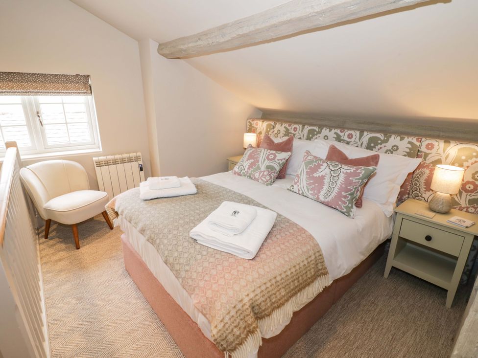 A bedroom with a bed and chair at Bay House Cottage in Broadway