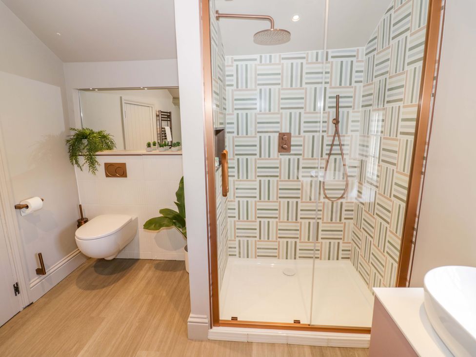 A bathroom with a shower, toilet, and sink at Bay House Cottage in Broadway