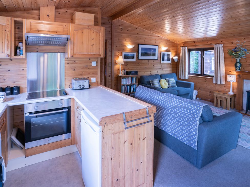 A living room with kitchen appliances and seating area at Watendlath in Keswick
