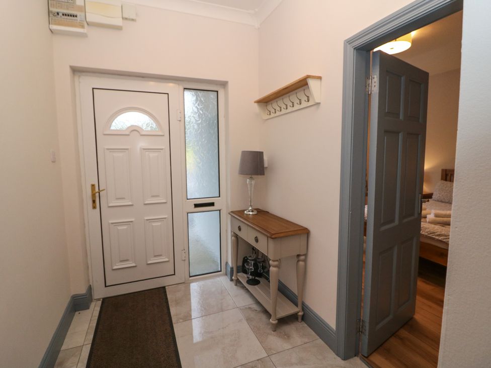 A hallway with a door, window, and console table at No 1 Lodge Wood, Kenmare, County Kerry