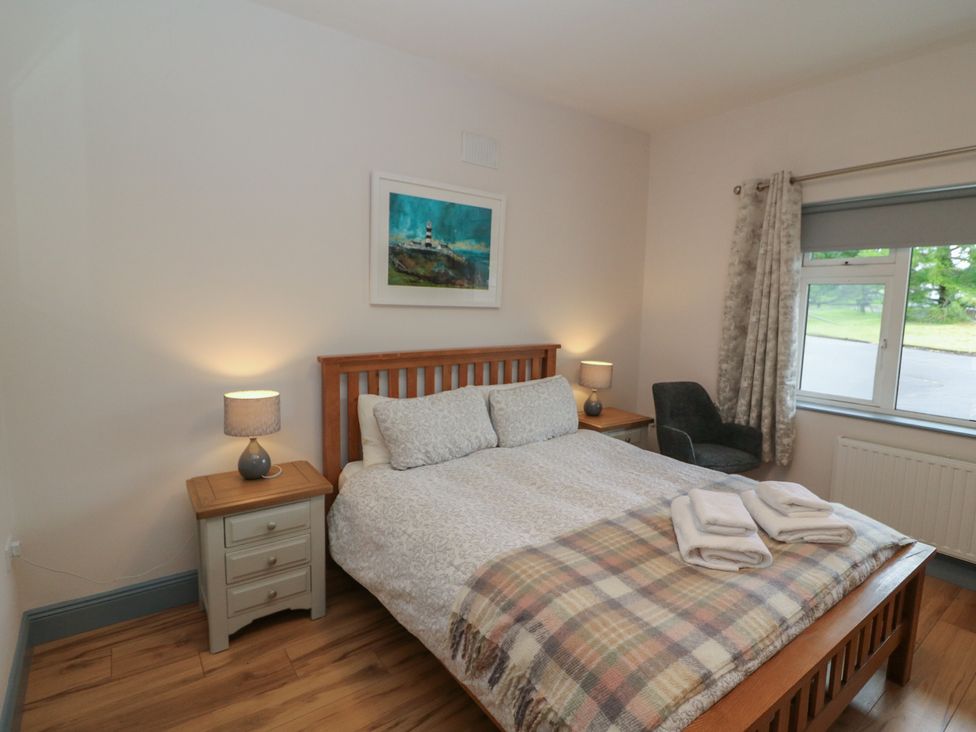 A bedroom with a bed and nightstand at No 1 Lodge Wood in Kenmare, County Kerry
