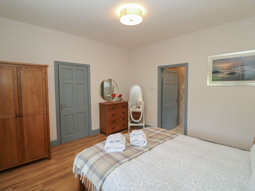A bedroom with a bed and wardrobe at No 1 Lodge Wood in Kenmare, County Kerry