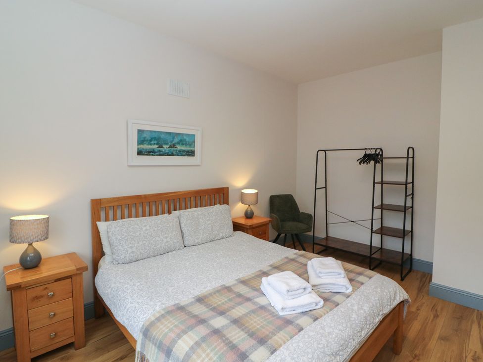 A bedroom with a bed and a wardrobe at No 1 Lodge Wood, Kenmare, County Kerry