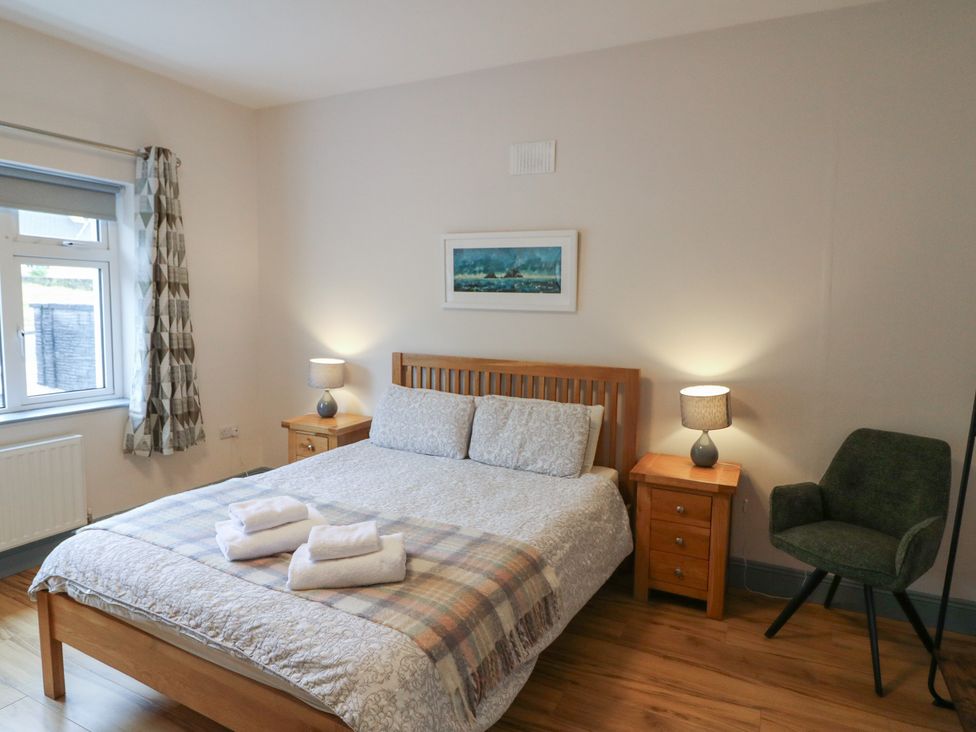 A bedroom with a bed and nightstands at No 1 Lodge Wood, Kenmare, County Kerry