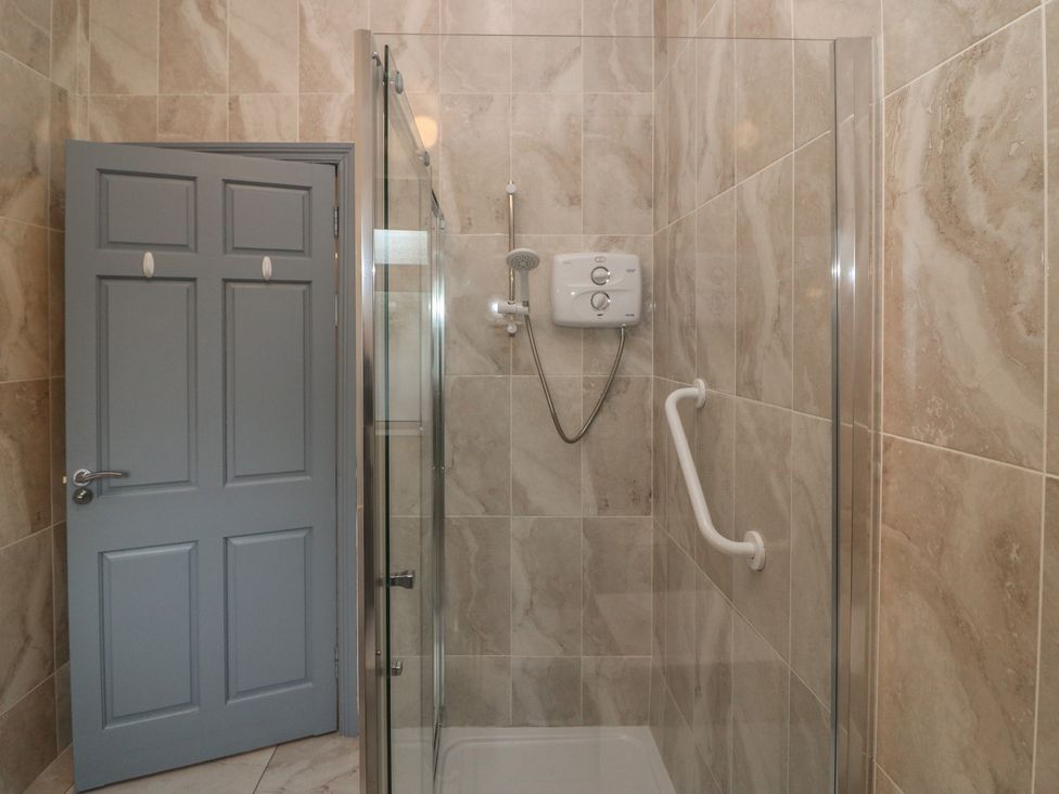 A shower stall with glass door and gray door at No 1 Lodge Wood, Kenmare, County Kerry