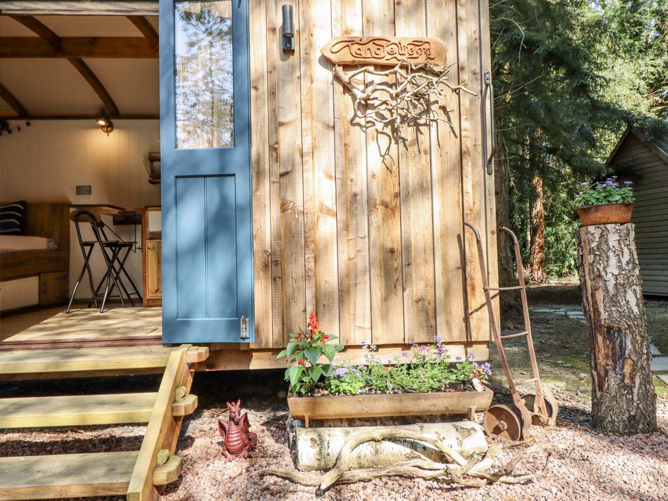An outdoor area with a wooden door and flower bed at Tanglewood Shepherds Hut in Welshpool