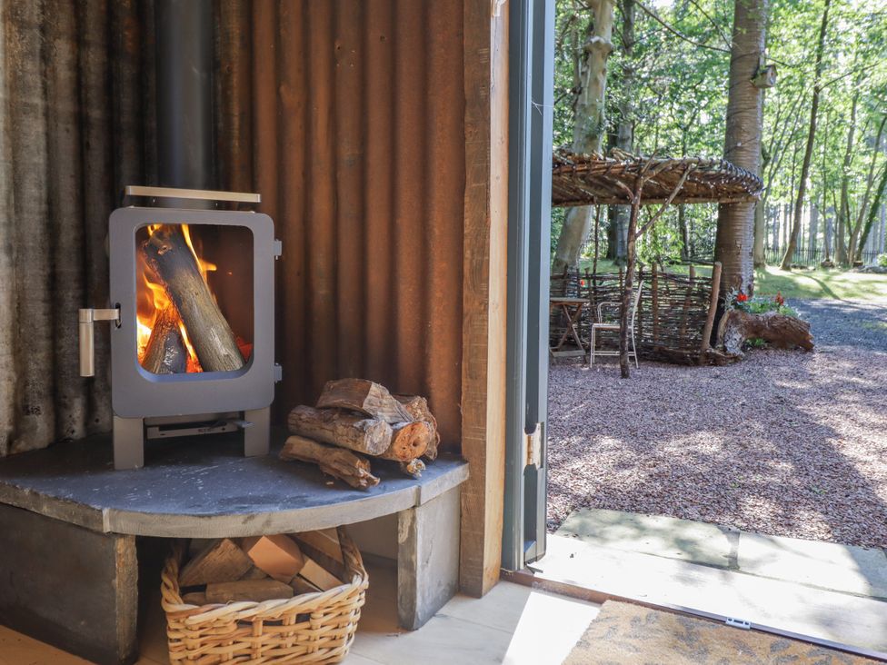 A room with a wood stove and firewood at Tanglewood Shepherds Hut in Welshpool