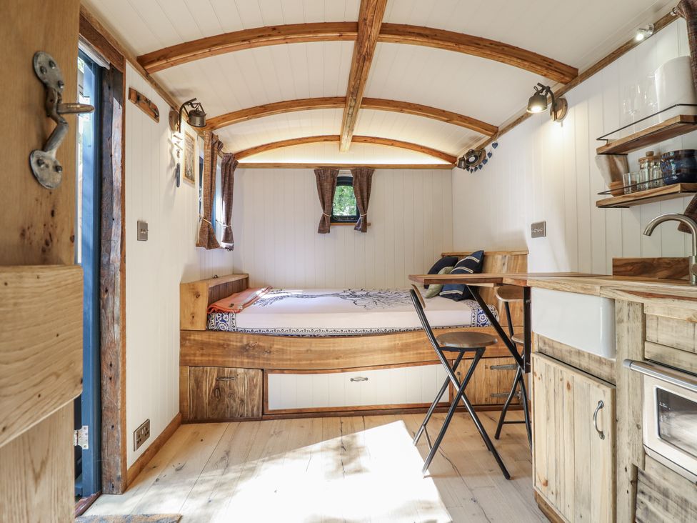 A living room with a bed and a kitchen area at Tanglewood Shepherds Hut in Welshpool