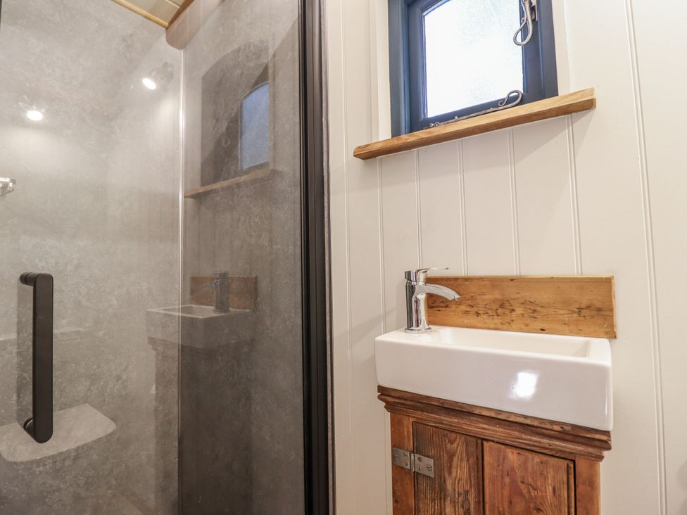A bathroom with a shower and a sink at Tanglewood Shepherds Hut in Welshpool