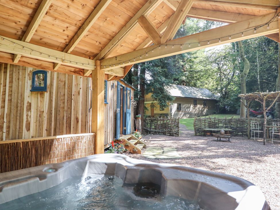 An outdoor seating area with a hot tub at Tanglewood Shepherds Hut Welshpool