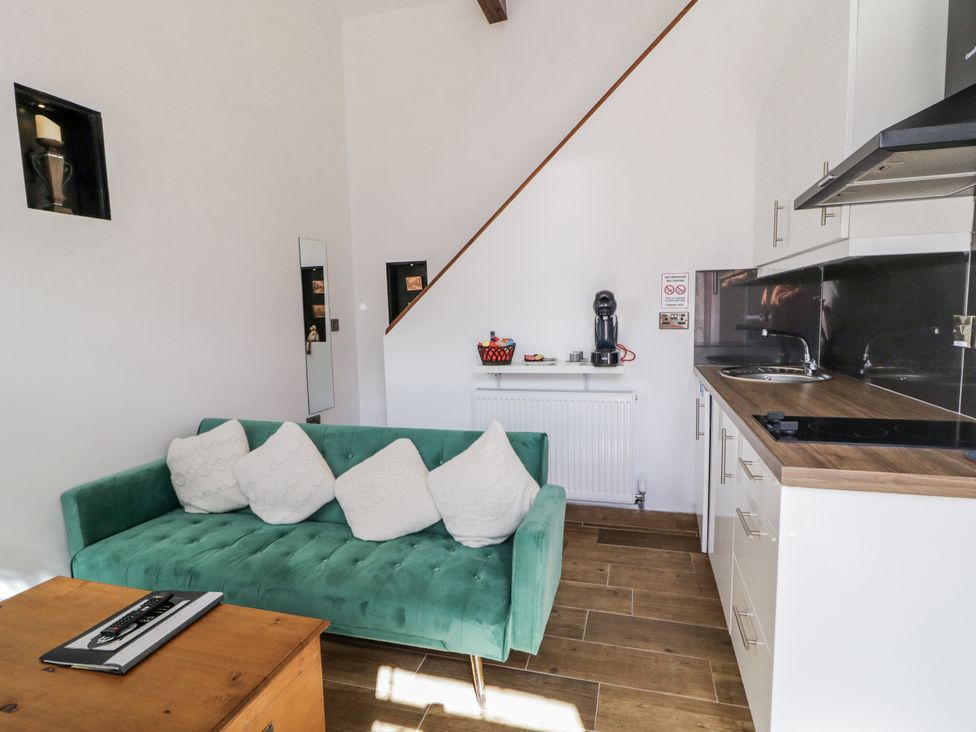 A living room with a sofa and kitchenette at Derrywilligan 1,2,3 Newry