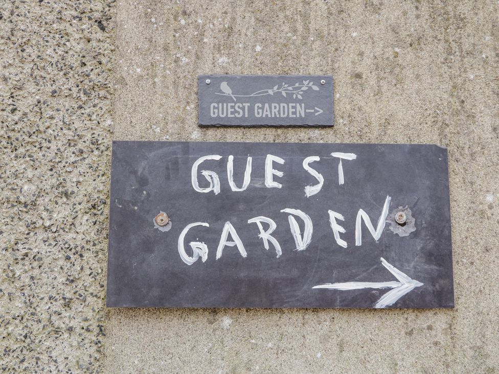 A sign indicating guest garden with an arrow at Derrywilligan 1,2,3 Newry