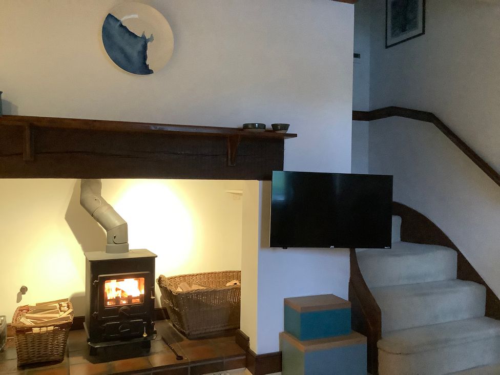 A living room with a stove, baskets, and a television at Old Town Cottage in Stratford-Upon-Avon