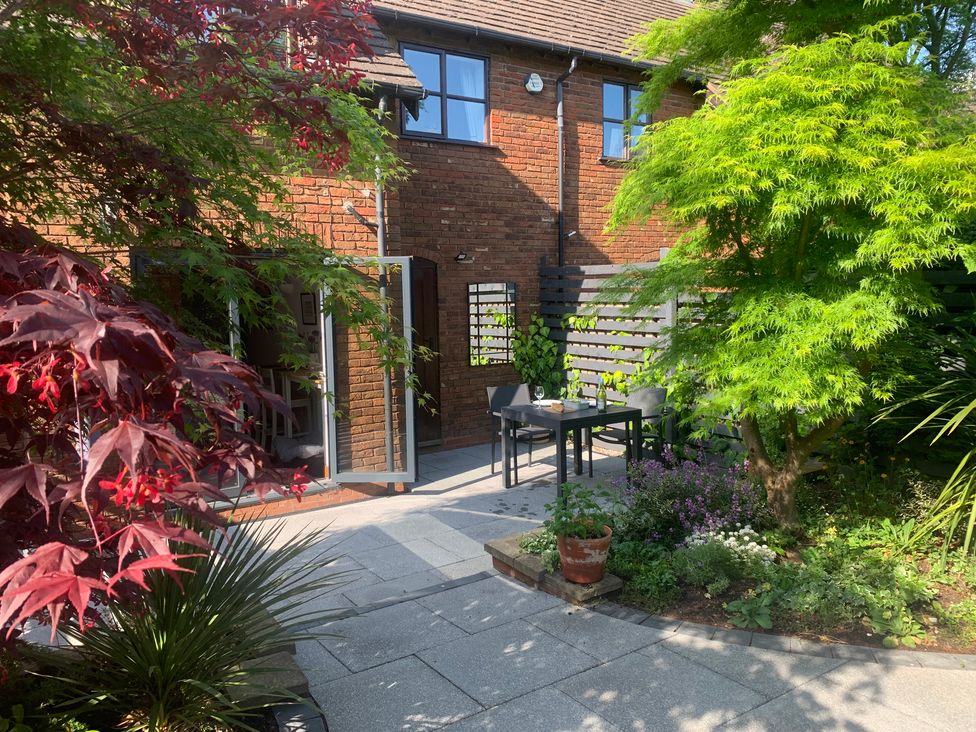 A garden with a glass table and chairs at Old Town Cottage in Stratford-Upon-Avon
