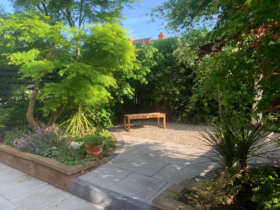 A garden with trees and a gravel area at Old Town Cottage Stratford-Upon-Avon