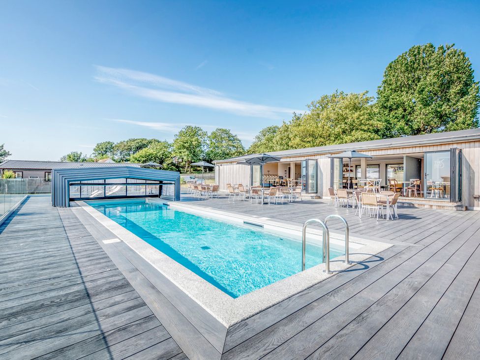 An outdoor pool area with a swimming pool and seating at Chalet 2 at Landscove Holiday Park Brixham