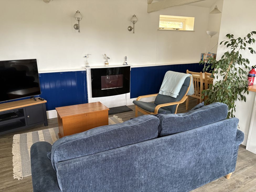 A living room with a television, sofa, and coffee table at Lighthouse Cottage in St Erme near Truro