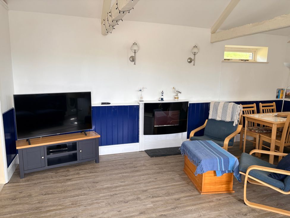 A living room with a tv, table, and seating at Lighthouse Cottage St Erme near Truro